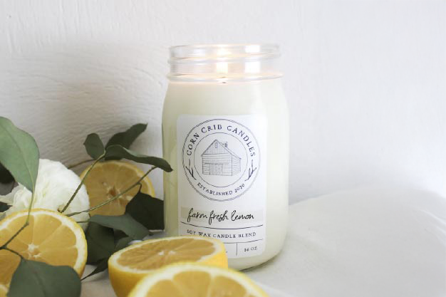 Corn Crib Candles candle with lemons and greenery on a white surface